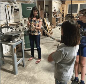 A woman teaching children how to use a machine.