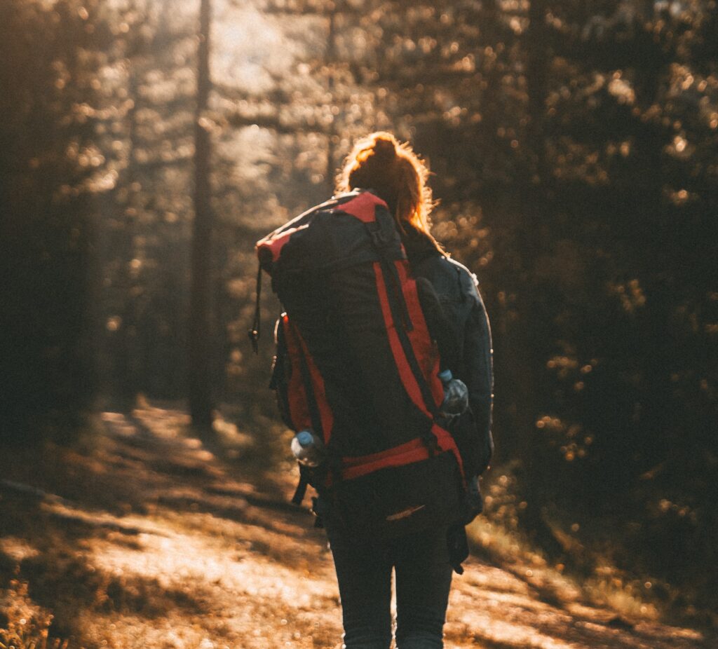 A person with a backpack walking on the side of a road.