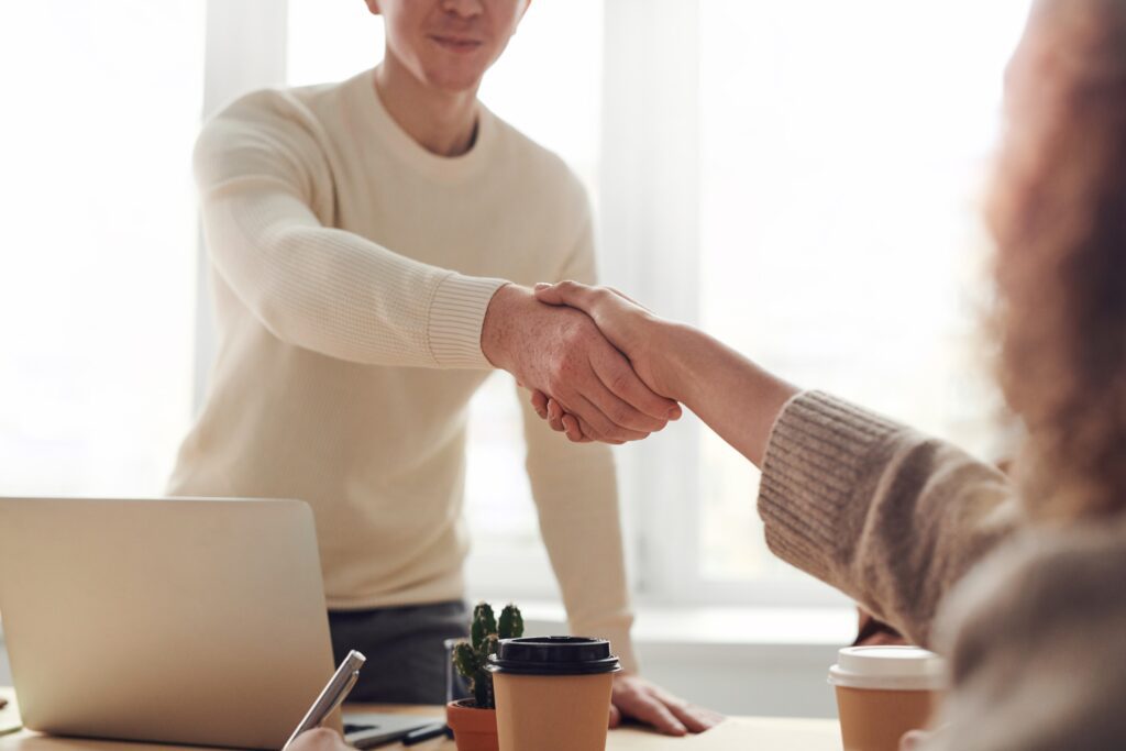 Two people shaking hands over a table